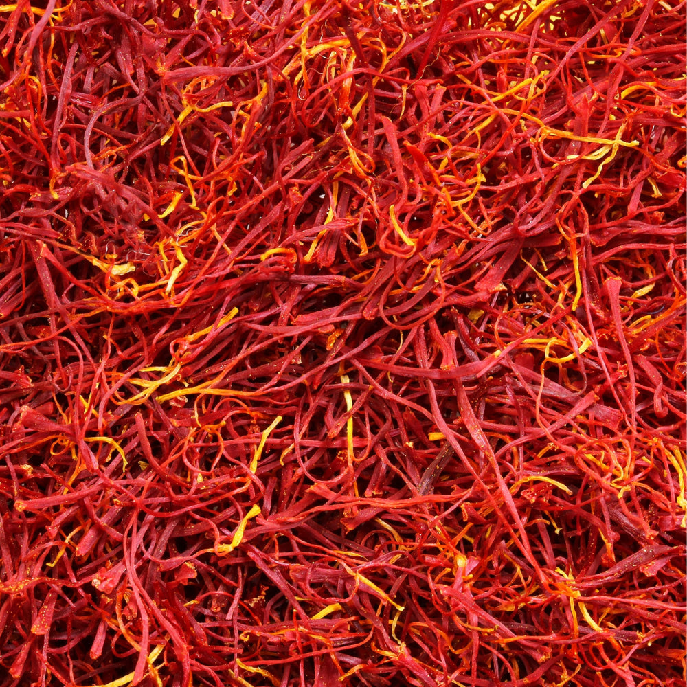 Gros plan sur des filaments de safran séché : de fines stigmates rouge vif mêlées de nuances jaune‑or, illustrant la haute pureté du safran utilisé dans nos gummies.
