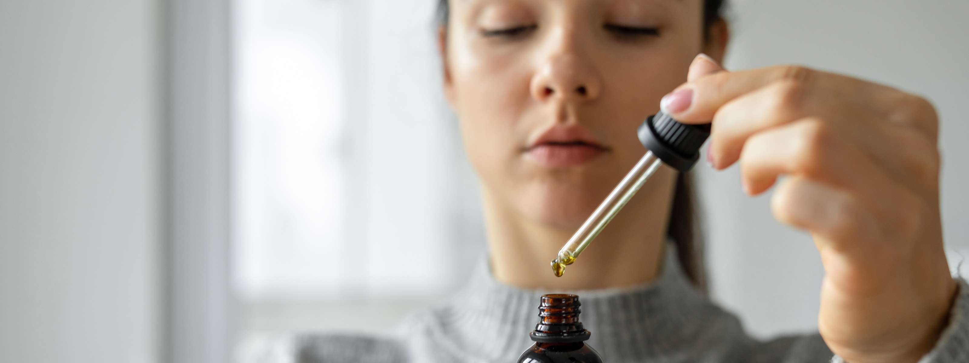Femme concentrée utilisant une pipette d’huile de CBD.