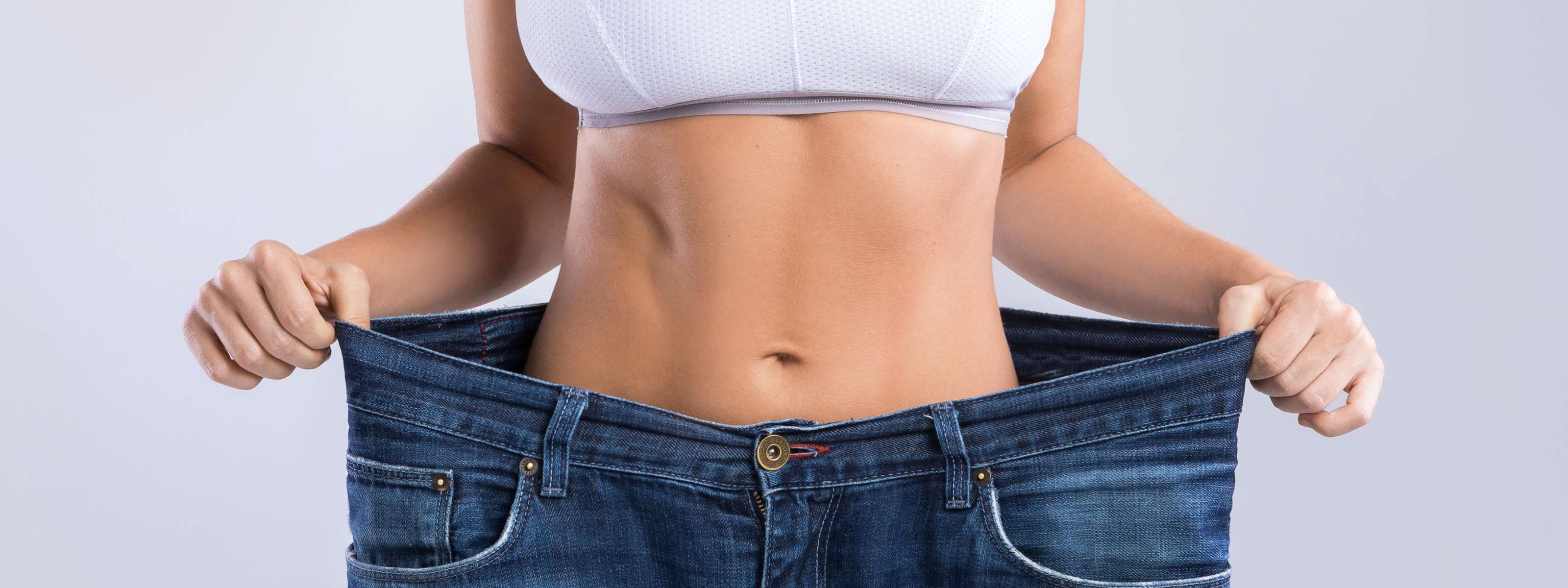 Femme montrant une perte de poids en tenant son pantalon trop grand.