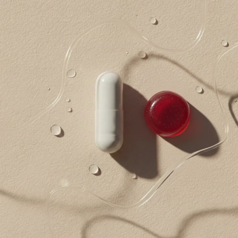 Gros plan sur une gélule blanche et un gummy rouge posés sur un fond beige avec des gouttes d’eau, illustrant la prise de collagène en complément alimentaire. Représentation symbolique de l’efficacité du collagène hydrolysé pris par voie orale pour stimuler la production naturelle de collagène dans la peau, les articulations, les tendons et les os.