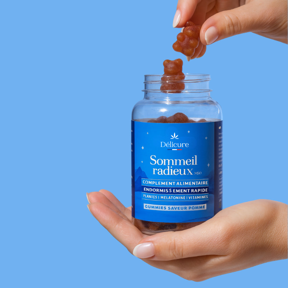 Main tenant un pot de gummies Délicure Sommeil Radieux, compléments alimentaires naturels à la mélatonine, aux plantes et vitamines, pour favoriser l’endormissement rapide et améliorer la qualité du sommeil.