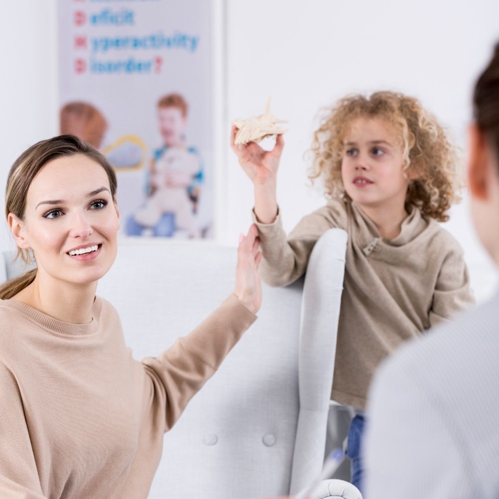 Scène positive parent-enfant avec professionnelle de santé en consultation — conclusion sur approche individualisée du TDAH.