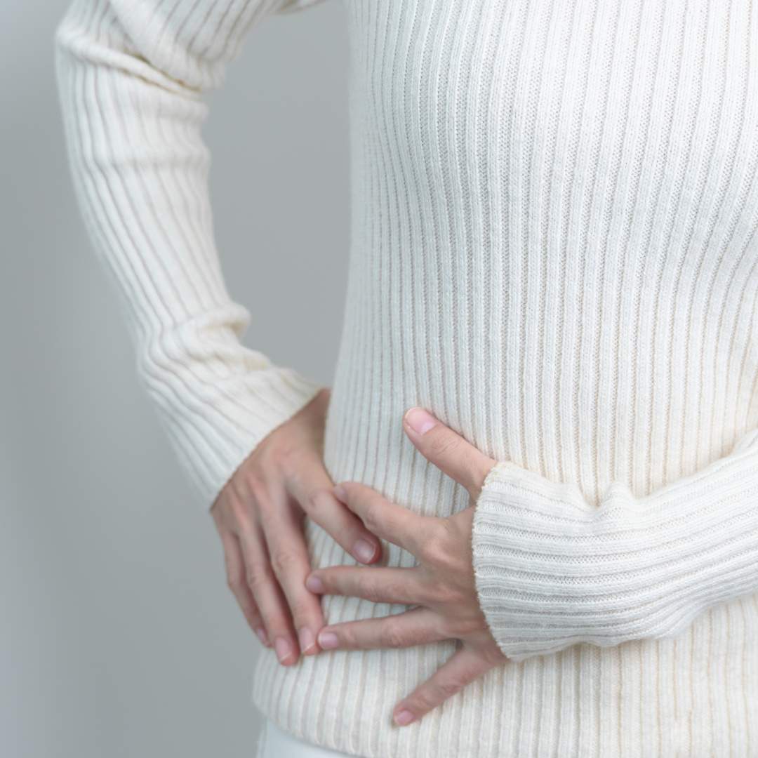 Douleur au rein droit illustrée par une femme tenant son abdomen, symptôme fréquent des calculs rénaux ou infections urinaires.