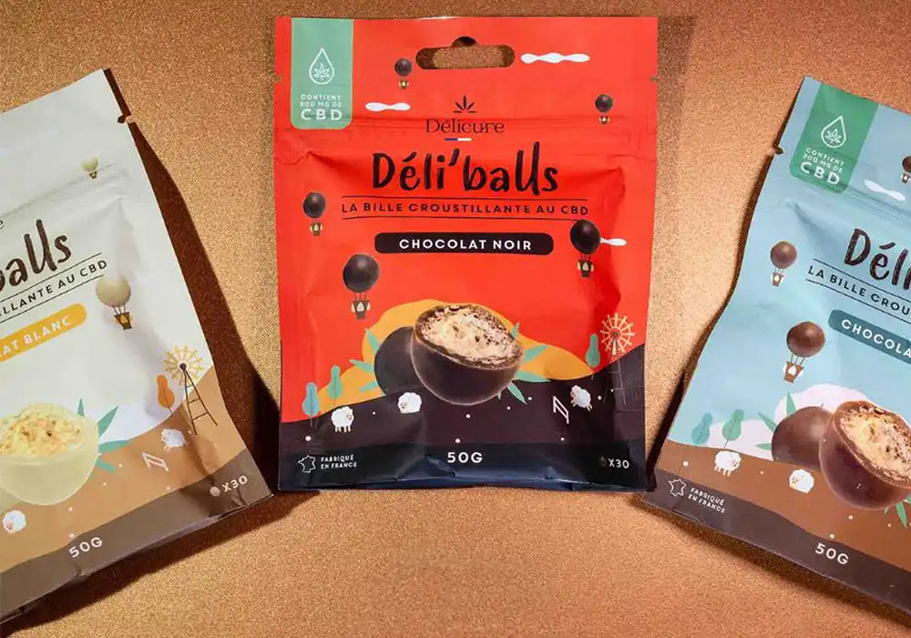 Image de trois paquets de billes croustillantes au CBD de la marque Délicure, nommées 'Déli'balls'. Les paquets sont présentés dans trois saveurs différentes : chocolat noir, chocolat au lait et chocolat blanc. Chaque paquet contient 50 grammes de billes croustillantes au CBD, conçues pour aider à gérer le stress et favoriser la relaxation. L'emballage coloré et attrayant met en avant la qualité française de ces produits, offrant une manière délicieuse et efficace de consommer du CBD.