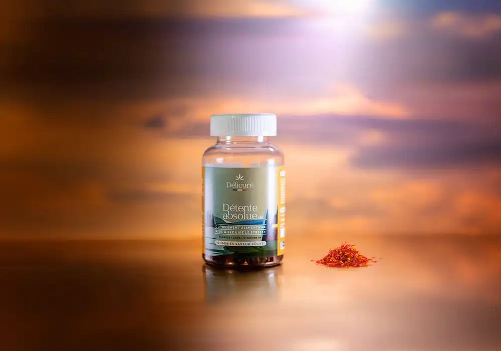 Image d'un flacon de gummies Délicure Détente Absolue, conçu pour aider à réduire le stress. Le flacon est posé sur une surface réfléchissante avec à sa droite du safran rouge de haute qualité, qui est un ingrédient des gummies anti-stress. En arrière-plan, un ciel aux teintes dorées et orangées suggère une ambiance de coucher de soleil, évoquant un sentiment de calme et de sérénité.