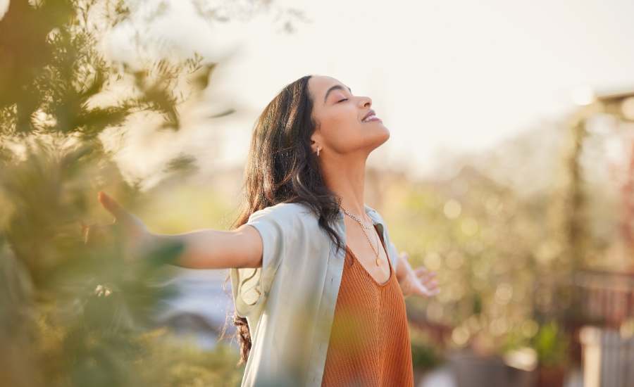 Una giovane donna che respira profondamente all'aperto, testimoniando l'effetto calmante e stimolante dello zafferano sull'umore e sulle prestazioni mentali