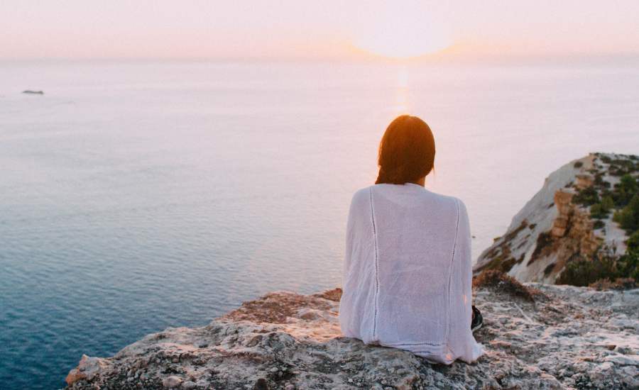 Young woman watching the sunrise, a zen image conveying the calm and harmony of this moment